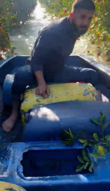 Sular altında kalan bahçesine kayıkla ulaştı